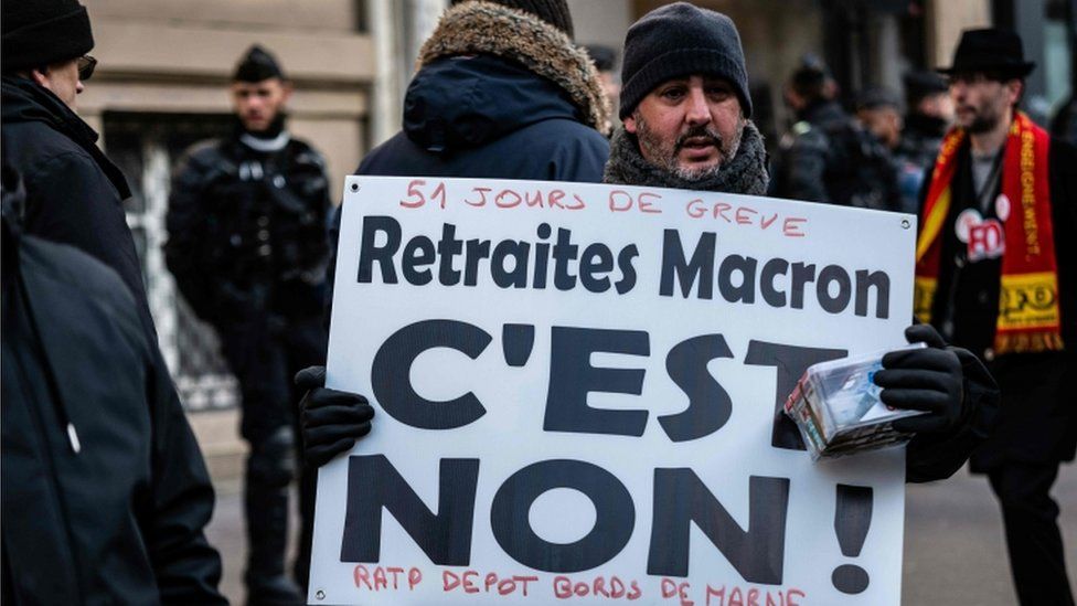 A man with a banner reading "Macron pensions : it's no" as he takes part in a demonstration in Paris on January 24, 2020