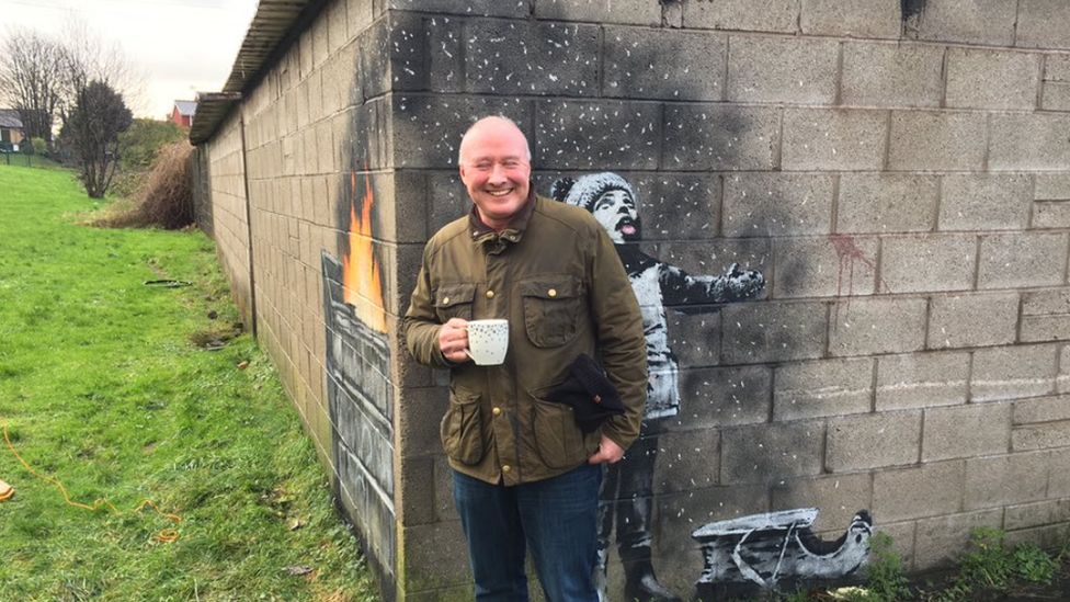 Ian Lewis standing in front of the suspected Banksy