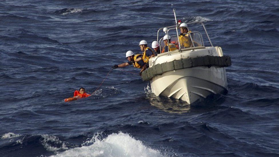 A handout picture made available by the Japan Coast Guard shows Japan Coast Guard rescue workers reaching out to the crew of a Chinese fishing boat that sunk following a collision with a Greek cargo vessel in the Senkaku (or Diaoyutai) Islands