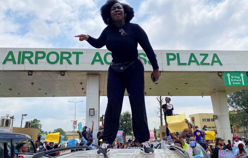 A demonstrator stands atop a vehicle and shouts slogans as others carry banners while blocking a road leading to the airport, during a protest over alleged police brutality, in Lagos, Nigeria October 12, 2020.