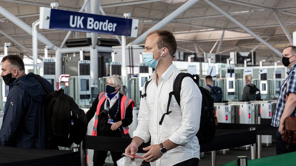A passenger wearing a face covering approaches passport control at Stansted airport in Essex on 20 July