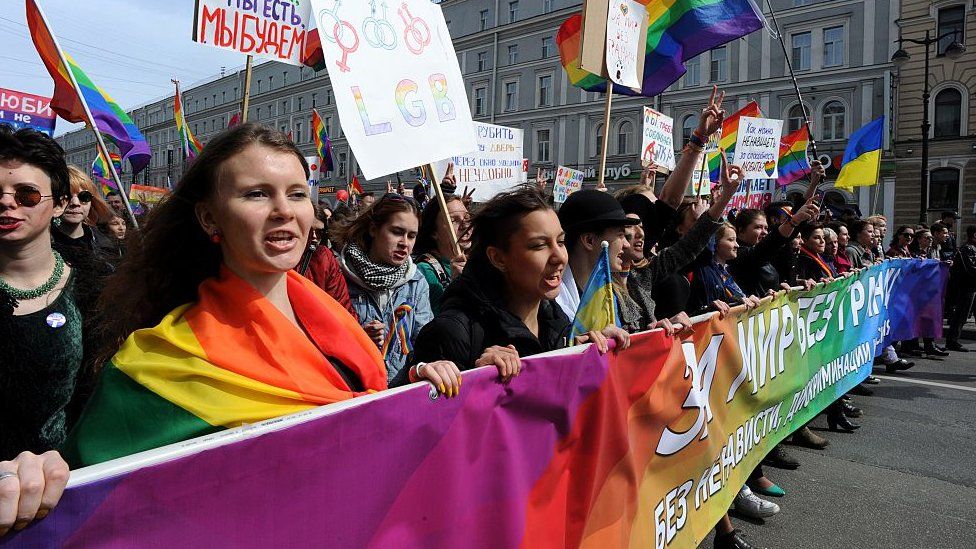 Members and supporters of the LGBT community hold a banner and waves rainbow flags as they take part in a May Day rally in Saint Petersburg on May 1, 2015