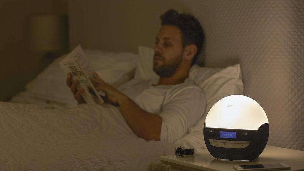 Lumie bedside light with man reading in bed