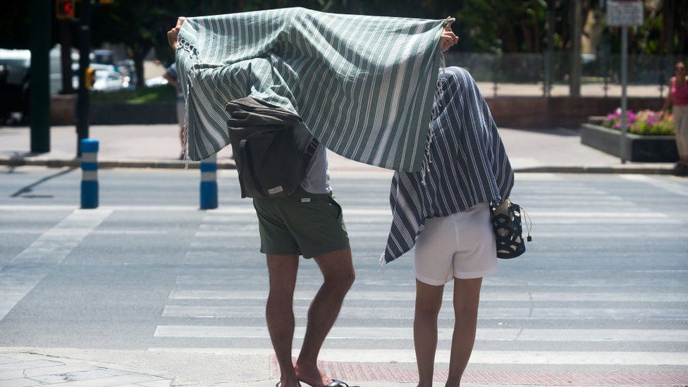 Tourists cover themselves with towels in the southern Spanish city of Malaga