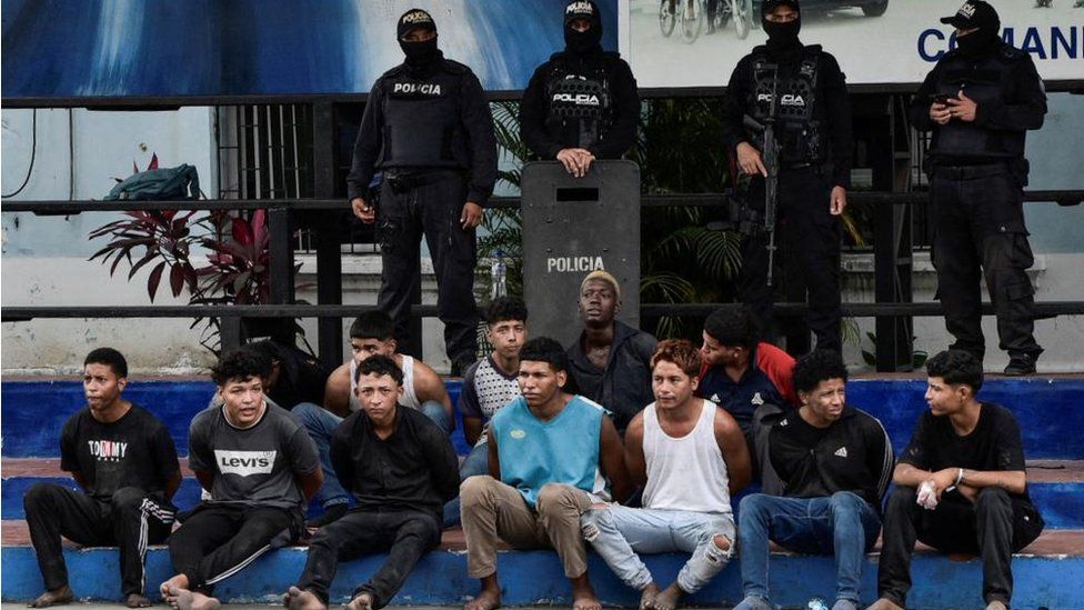 Police officers stand behind a group of detainees in Guayaquil, Ecuador on 10 January 2024.
