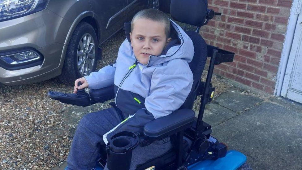 Young boy in an electric wheelchair looking to camera