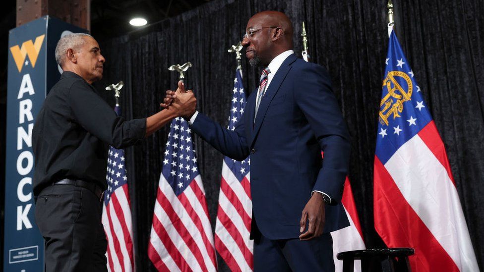 Former U.S. President Barack Obama clasps hands with Georgia Democratic Senate candidate U.S. Sen. Raphael Warnock