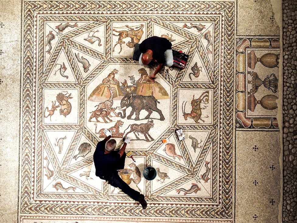 Workers clean a restored Roman-era mosaic after it was put on display at its original site in Lod, Israel, on 27 June 2022