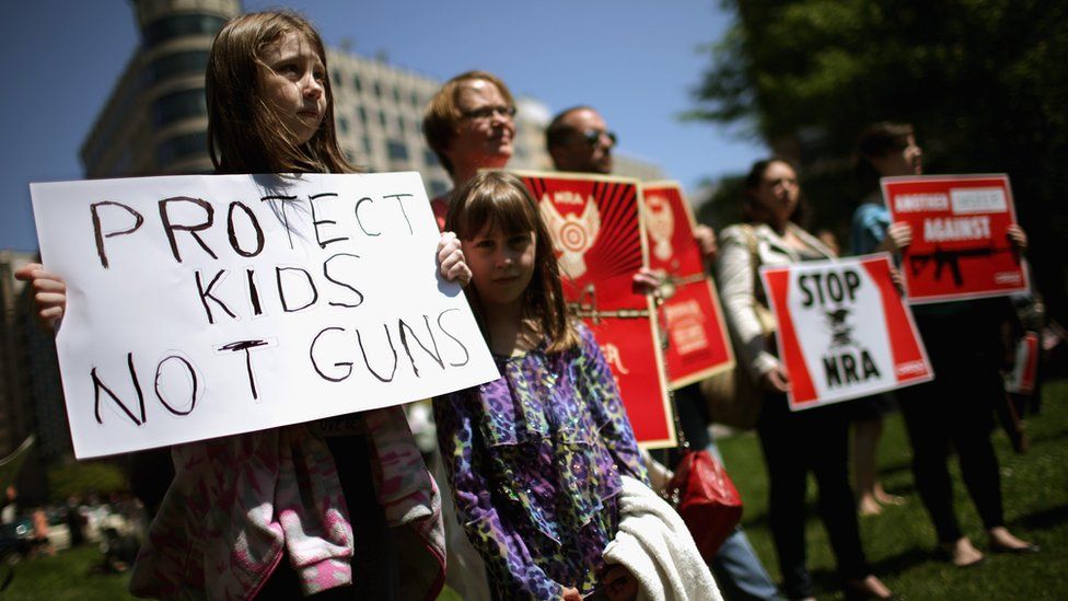 Anti-gun violence demonstrators hold signs condemning the National Rifle Association in Washington, DC.