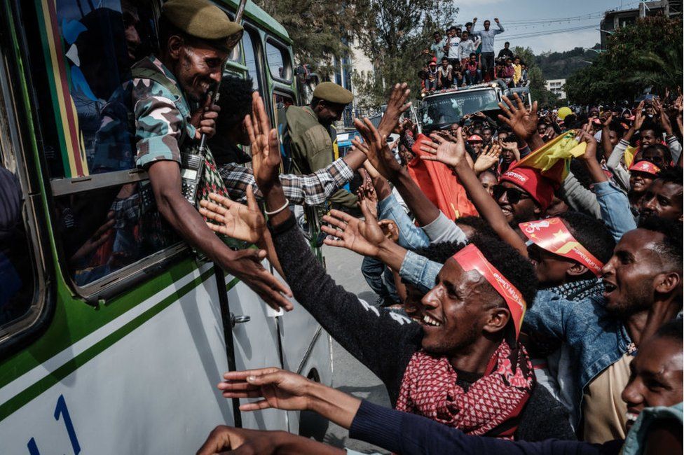 People try to shake hands with soldiers of Tigray Defence Force (TDF) as they arrive in Mekelle