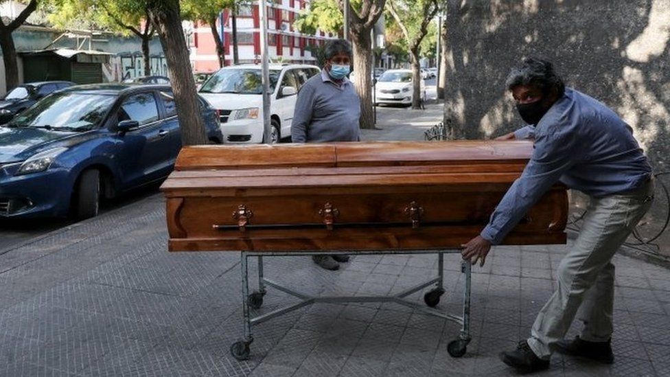 Funeral home workers move a casket outside a morgue at a hospital area, during the coronavirus disease (COVID-19) pandemic, in Santiago, Chile April 8, 2021