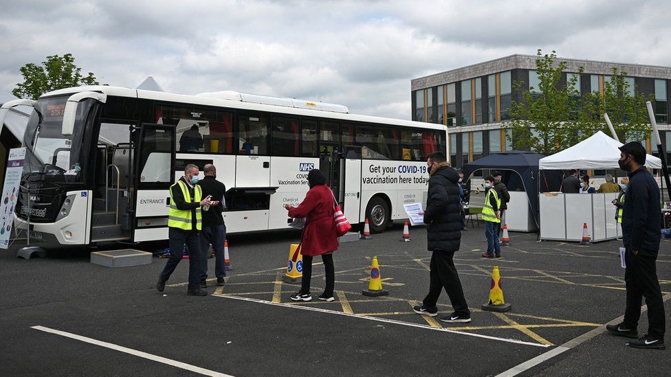 People queue for a vaccination at a bus in Bolton