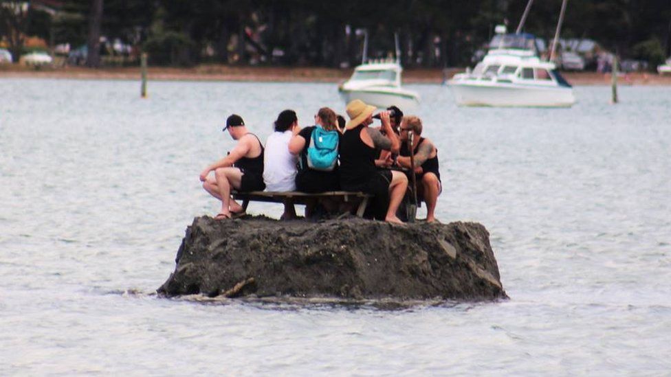 New Year revellers enjoy a drink on a special sand island they constructed earlier in the Tairua estuary on the Coromandel peninsula