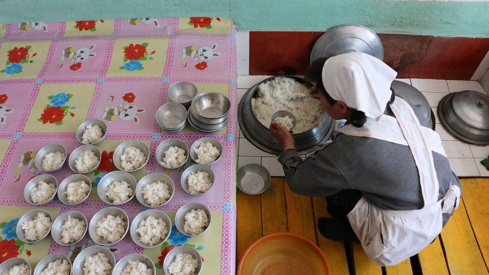 woman seen from above serving rice into small bowls
