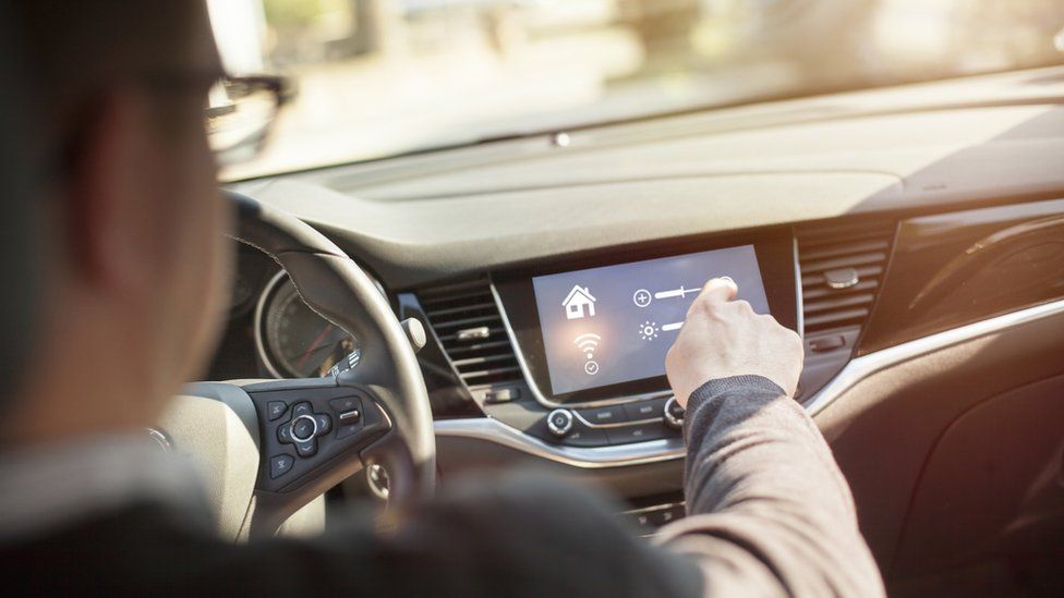 A man interacts with the screen in his connected car