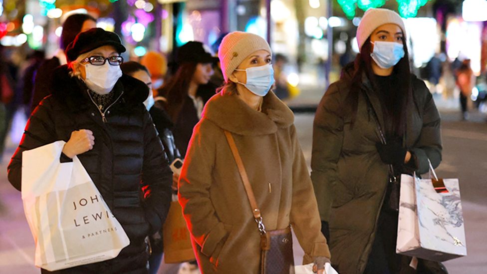 Shoppers wearing face masks walk along Oxford Street in central London on 2 December 2021
