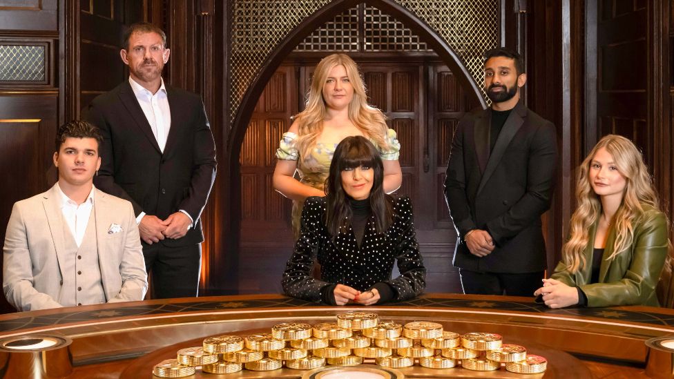 The Traitors contestants Harry Clark. Andrew Jenkins, Evie Morrison, Jaz Singh and Mollie Pearce pictured with presenter Claudia Winkleman