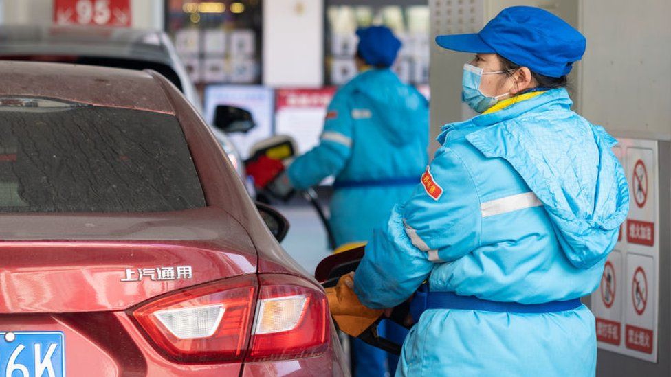Работник АЗС в Китае заправляет машину топливом.