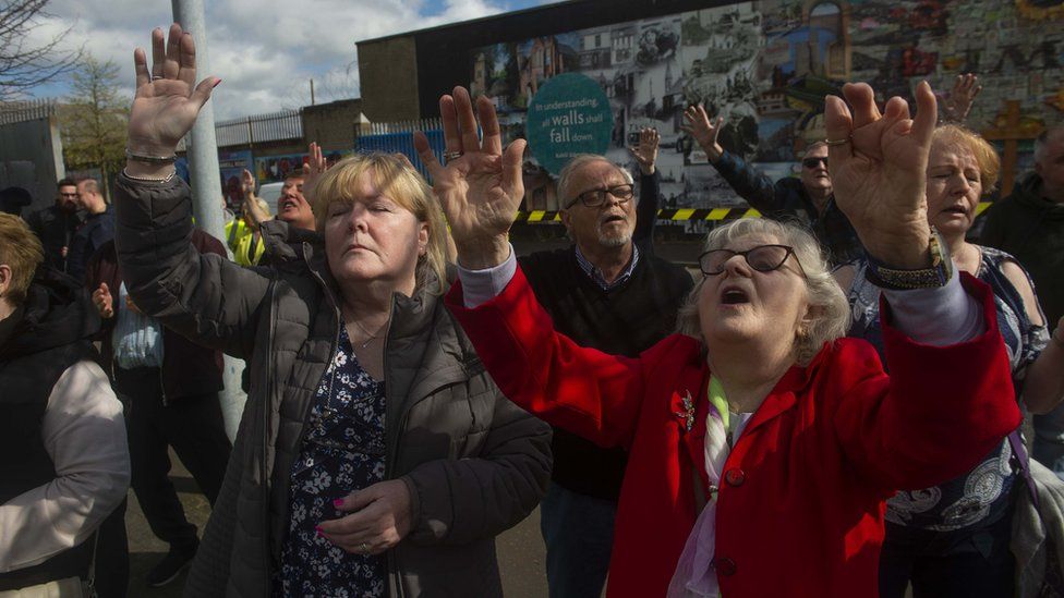 People in west Belfast sing and raise their hands as they gather to mark the 25th anniversary of the Good Friday Agreement