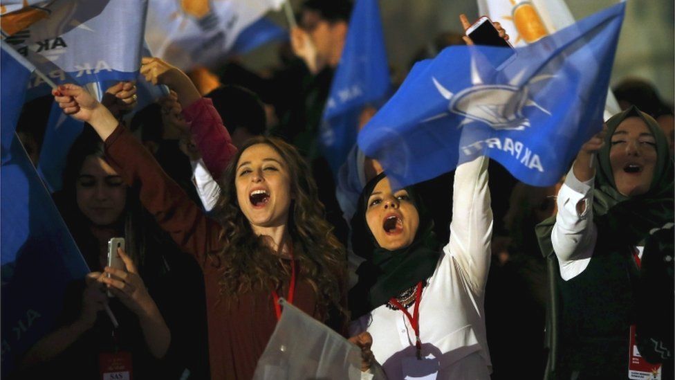Women wave flags outside the AK Party headquarters in Ankara