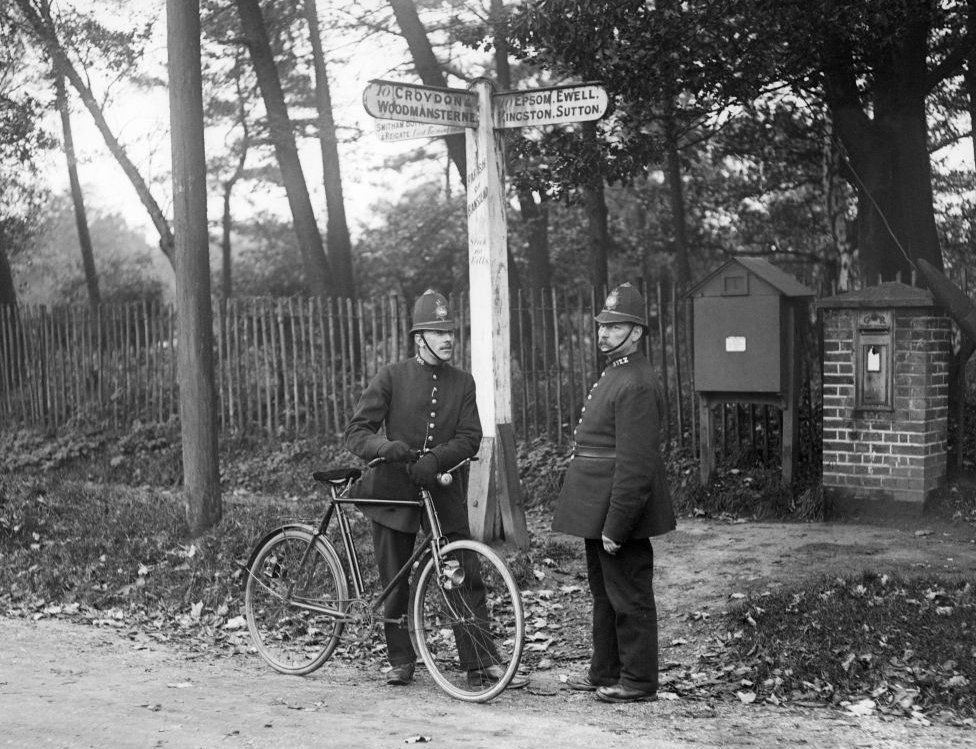 11th November 1916: Two policeman stop to talk under a signpost in Banstead, south London. (Phot