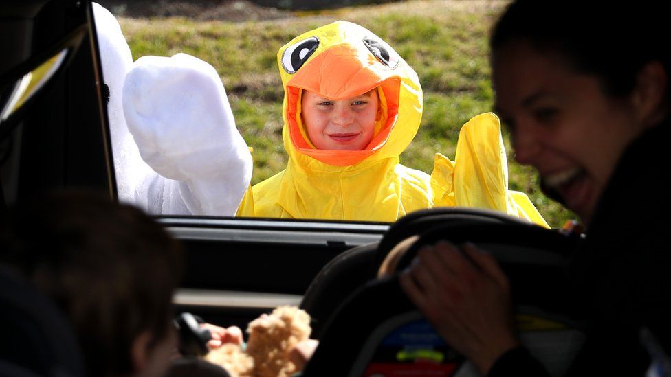 Boston Phillips, 11, dressed as a chick, waves to children during a drive-through Easter photo session at StoryHeights Church on April 11, 2020 in Newton, Massachusetts.