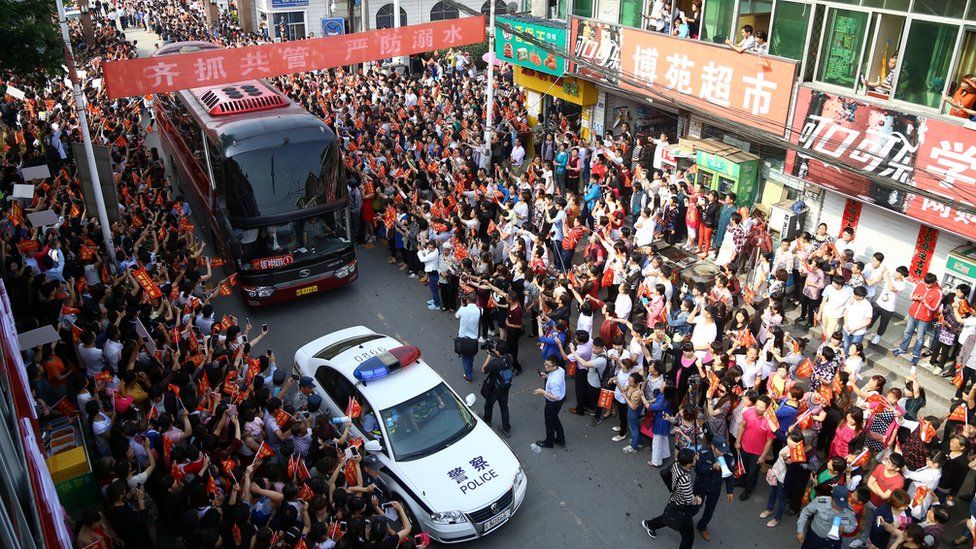 Police vehicles clear a path for students leaving school to attend China"s annual national college entrance exam or "gaokao" as people see the them off in Liu"an