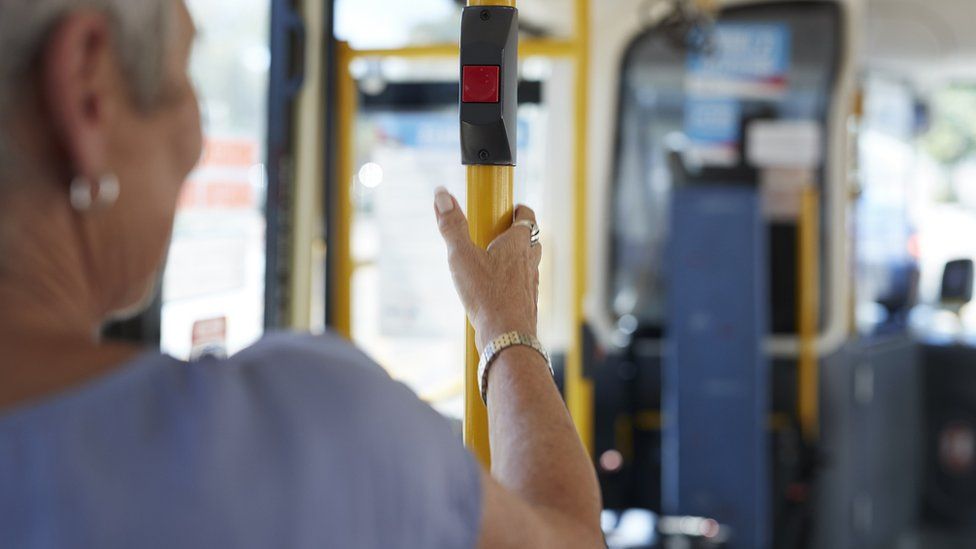 A woman holding onto an upright rail on a bus