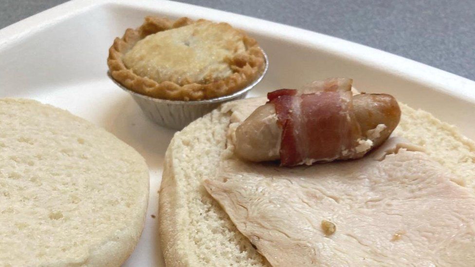 A dry bread roll with a slice of turkey, pig in blanket and mince pie