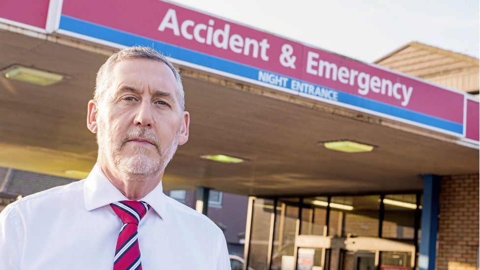 An image of Dr Ian Harvey wearing a shirt and tie outside the A&E entrance of the Countess of Chester Hospital