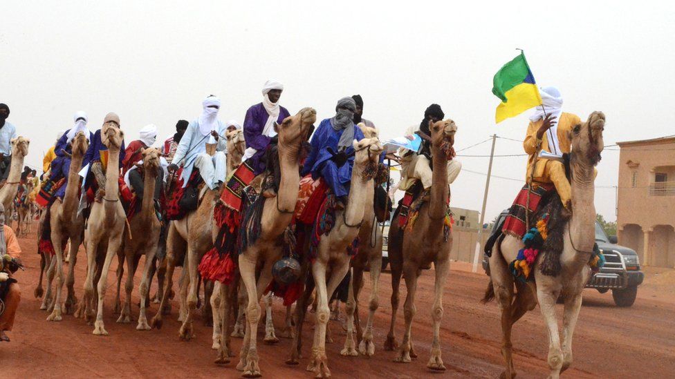 Dignitaries in traditional attire ride camels to the stadium in Gao on July 18, 2018 as the incumbent Malian President Ibrahim Boubacar Keita is expected to address a campaign rally.