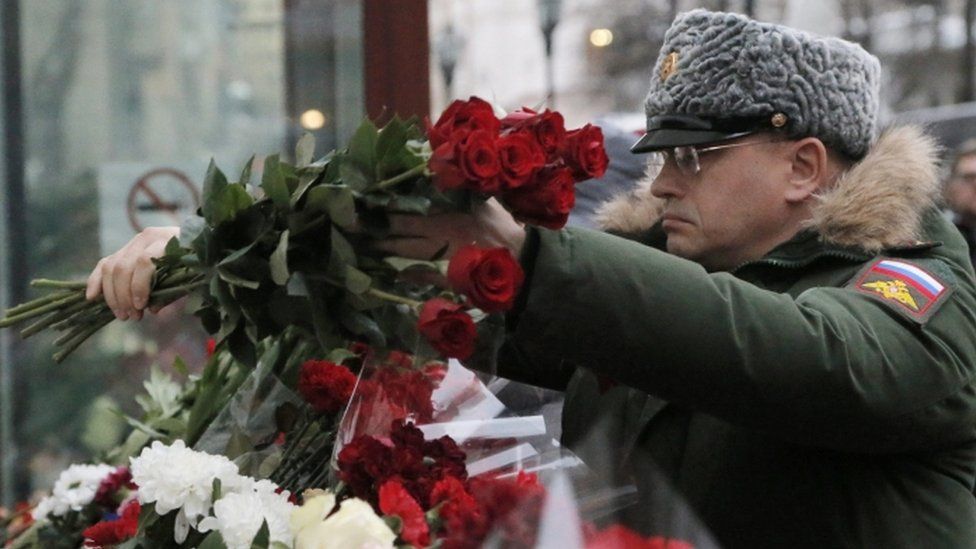 A Russian soldier places flowers at a small memorial outside the home stage of the Alexandrov choir in Moscow, Russia, 26 December 2016