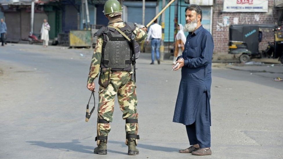 An Indian paramilitary troopers stops an elderly Kashmiri man during a curfew in Srinagar (08 July 2017)