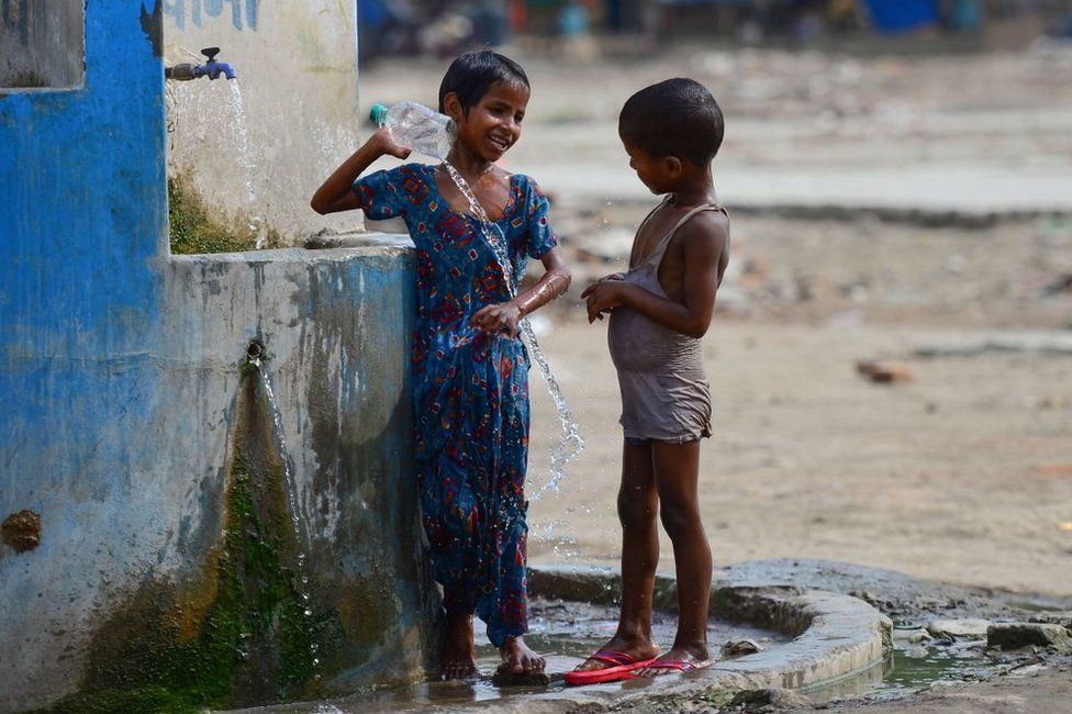 Indian children take a bath at a roadside tap during a hot summer afternoon in Allahabad on June 2, 2019