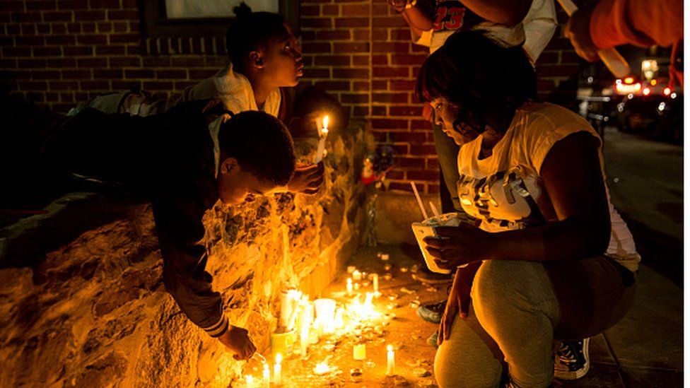 Kids laying candles for Freddie Grey
