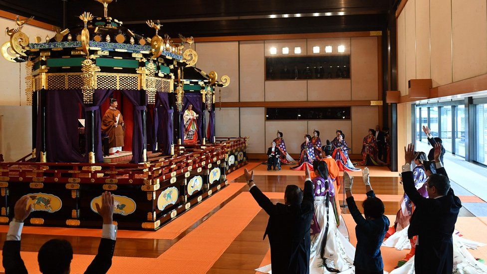 Japan"s Prime Minister Shinzo Abe (R) shouts banzai cheer for Emperor Naruhito (top L) and Empress Masako