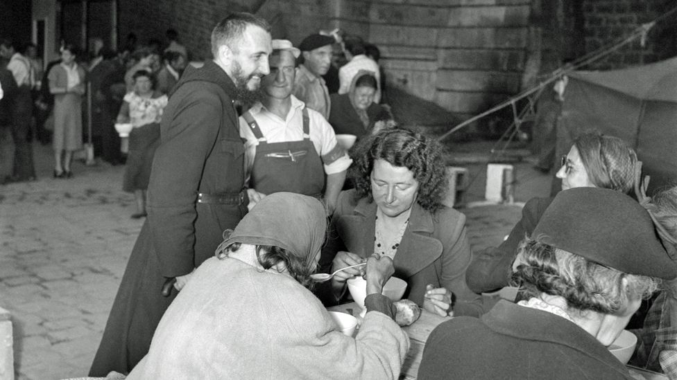 A picture taken on August 3, 1955 shows French Catholic priest Abbé Pierre (L) visiting the homeless people sheltered in the tent village built by the Emmaus companions quai Henri IV along the river Seine bank.