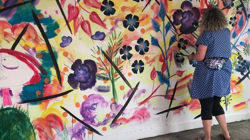 Rose Popay painting a wall with colourful flowers