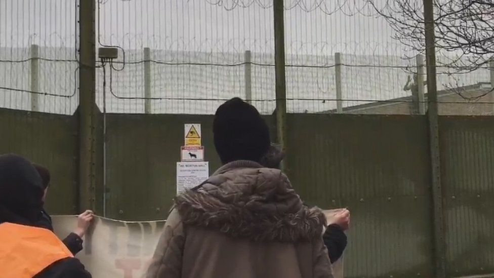 Man climbing a fence inside a detention centre