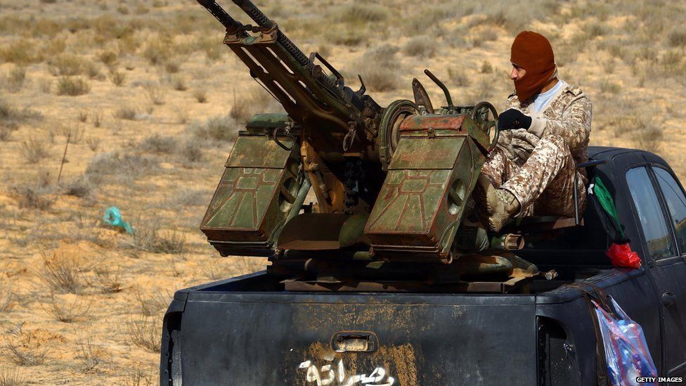militia sits on a pick up truck mounted with a machine gun during clashes with forces loyal to Libya"s government