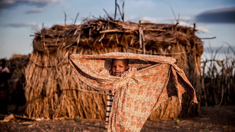 A child belonging to the Turkana community stands next to the family house, covered with a blanket, in the early morning hours in an arid dry area in Morungole, Turkana County, Kenya, on October 3, 2019