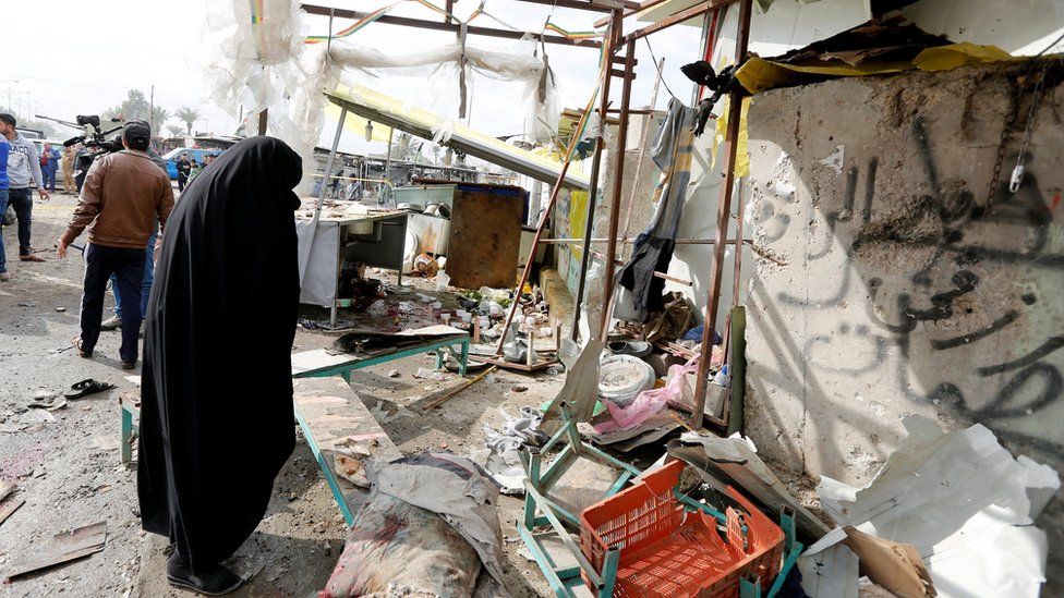 A woman looks at the scene of a suicide car bomb attack in Sadr City district of Baghdad (2 January 2017)