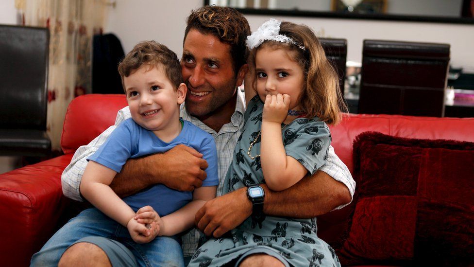 Noah and Lahala Elamine pose for a picture with their father Ali Elamine in their family home in Beirut, Lebanon