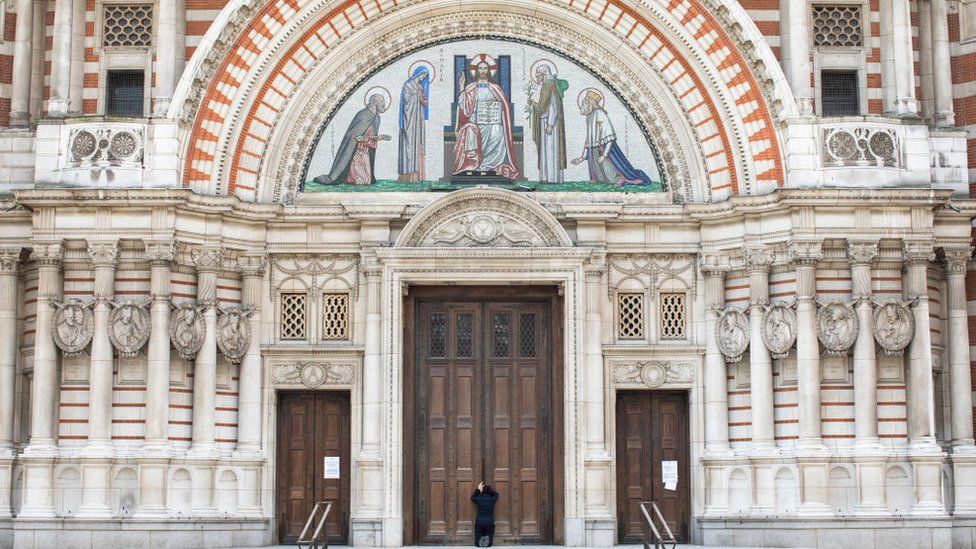Woman prays in front of a closed Westminster Cathedral on Sunday