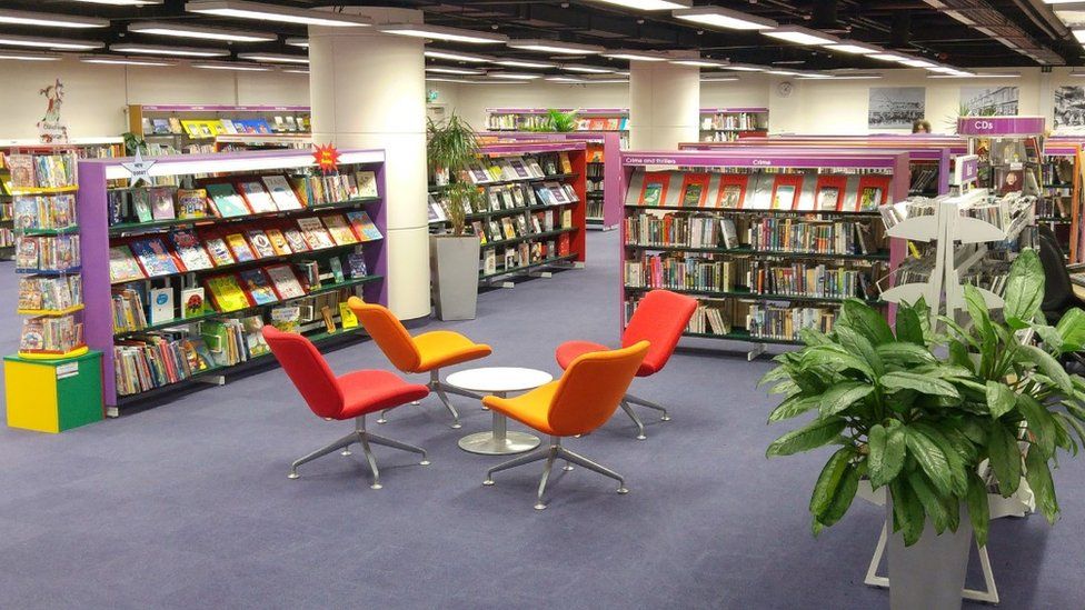 inside of Eastleigh Library, which has purple carpet, a large green plant and lots of bookshelves