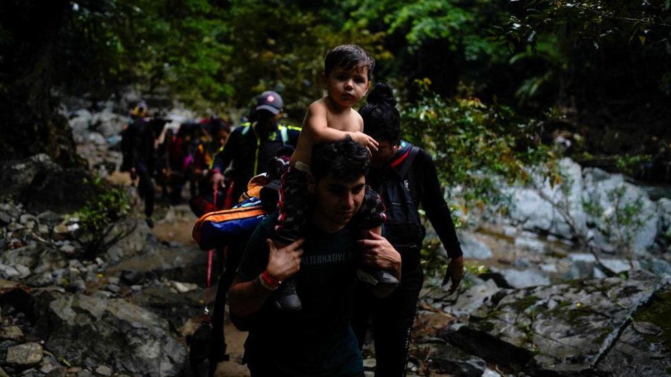 A Venezuelan migrant carries his son on his shoulders while walking through the Darien Gap, as they continue their journey to the U.S. border, in Acandi, Colombia July 9, 2023.
