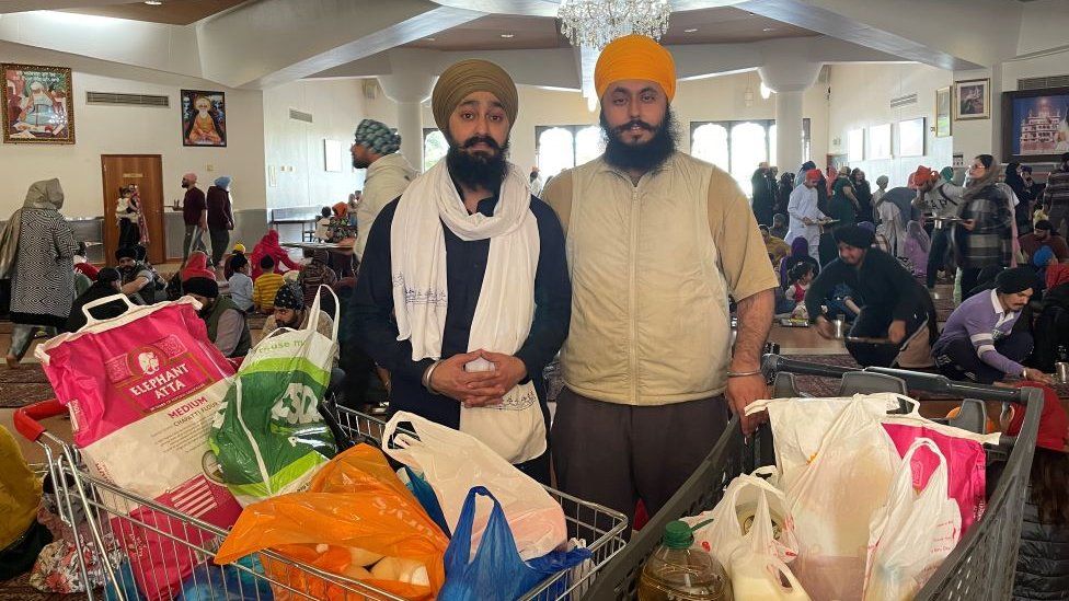 Onkar Singh (right) stands with trolleys full of donated food.