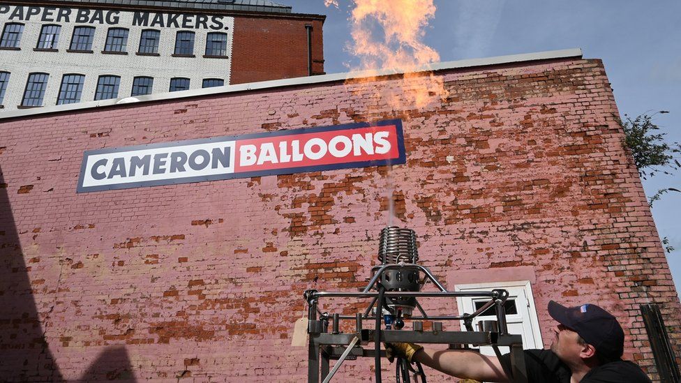 A man fires a hot air balloon burner in the yard of Cameron Balloons in Bristol, with the flame rising