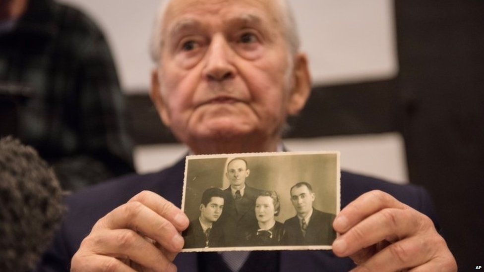 Auschwitz concentration camp survivor Leon Schwarzbaum presents an old photograph showing himself, left, next to his uncle and parents who all died in Auschwitz during a press conference in Detmold, Germany, Wednesday, Feb. 10, 2016.