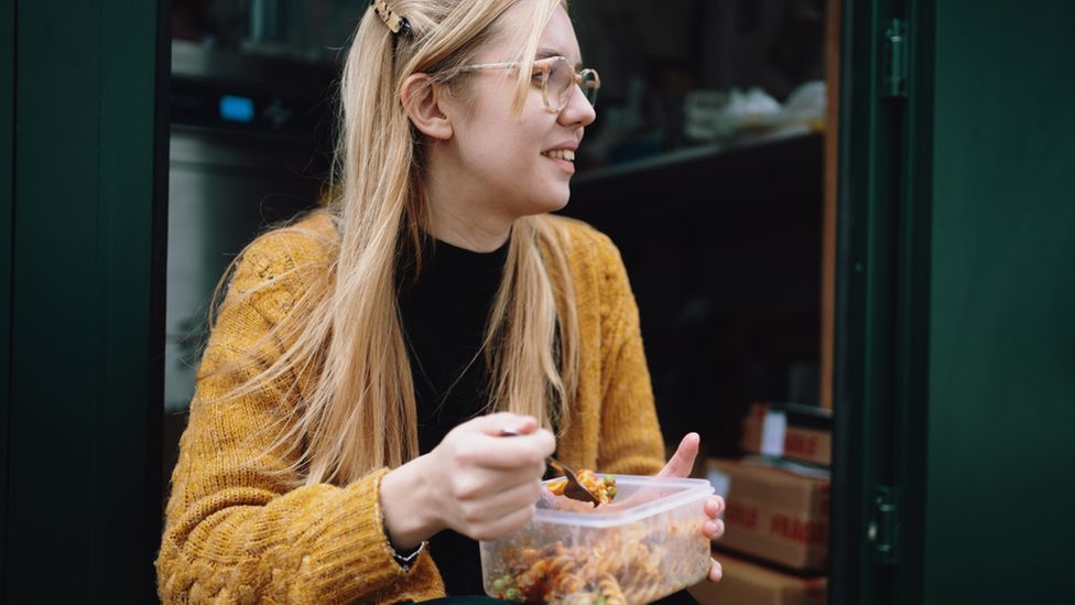 Woman eats food from plastic container